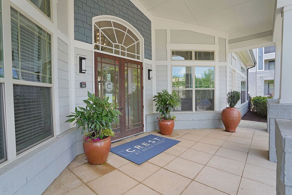 Exterior building entrance with glass doors, large windows, and potted plants at a residential complex.