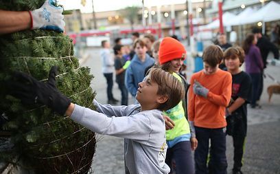 A group of children are standing around a christmas tree.