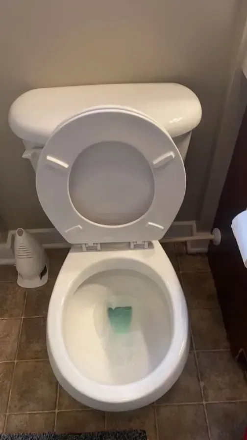 A white toilet is sitting on a tiled floor in a bathroom.