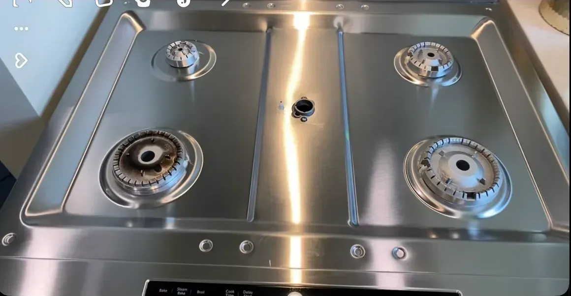 A stainless steel stove top with four burners and a control panel.