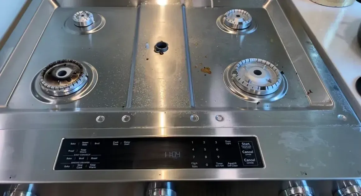 A stainless steel stove top with four burners and a digital display.