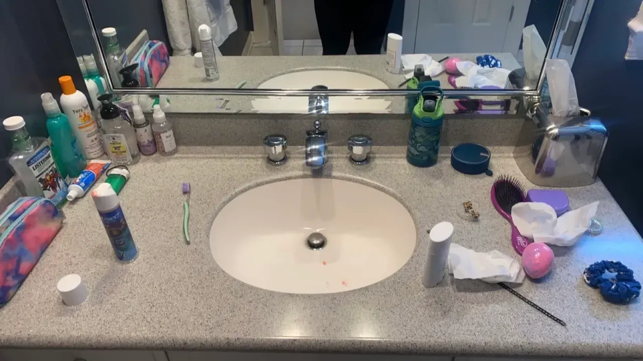 A bathroom counter with two sinks and a mirror.