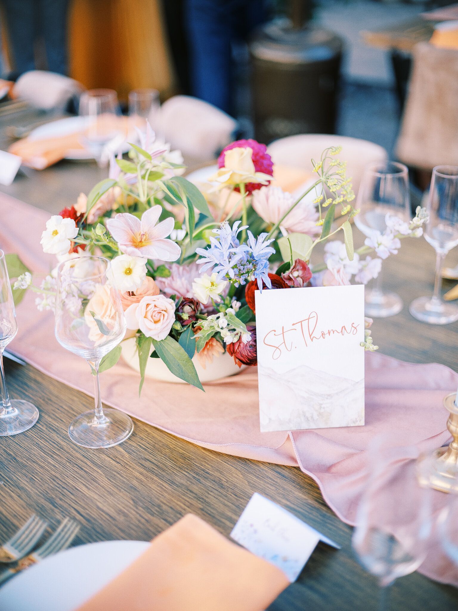 A table with a vase of flowers and a place card on it.