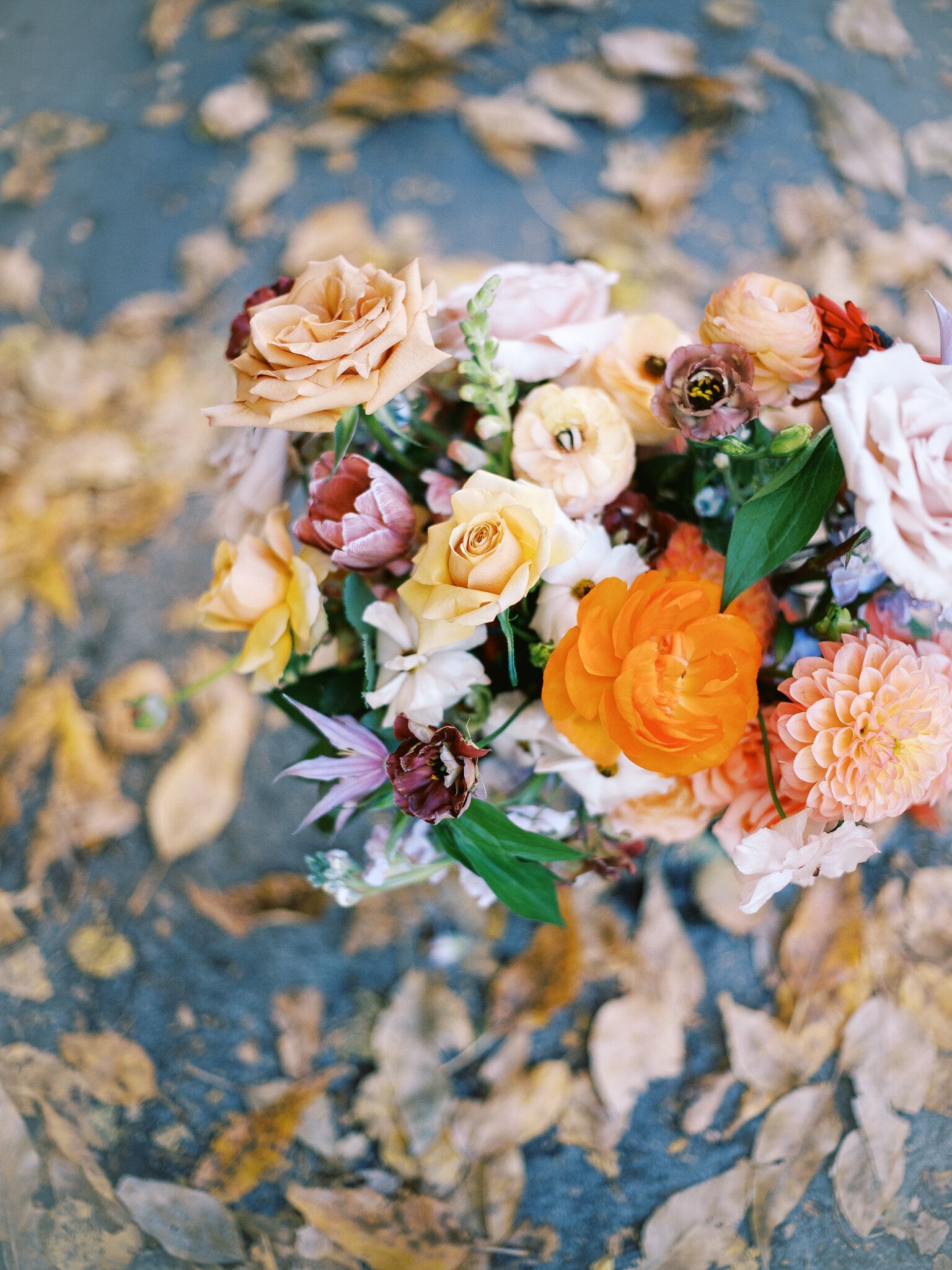 A bouquet of flowers sitting on top of a pile of leaves.