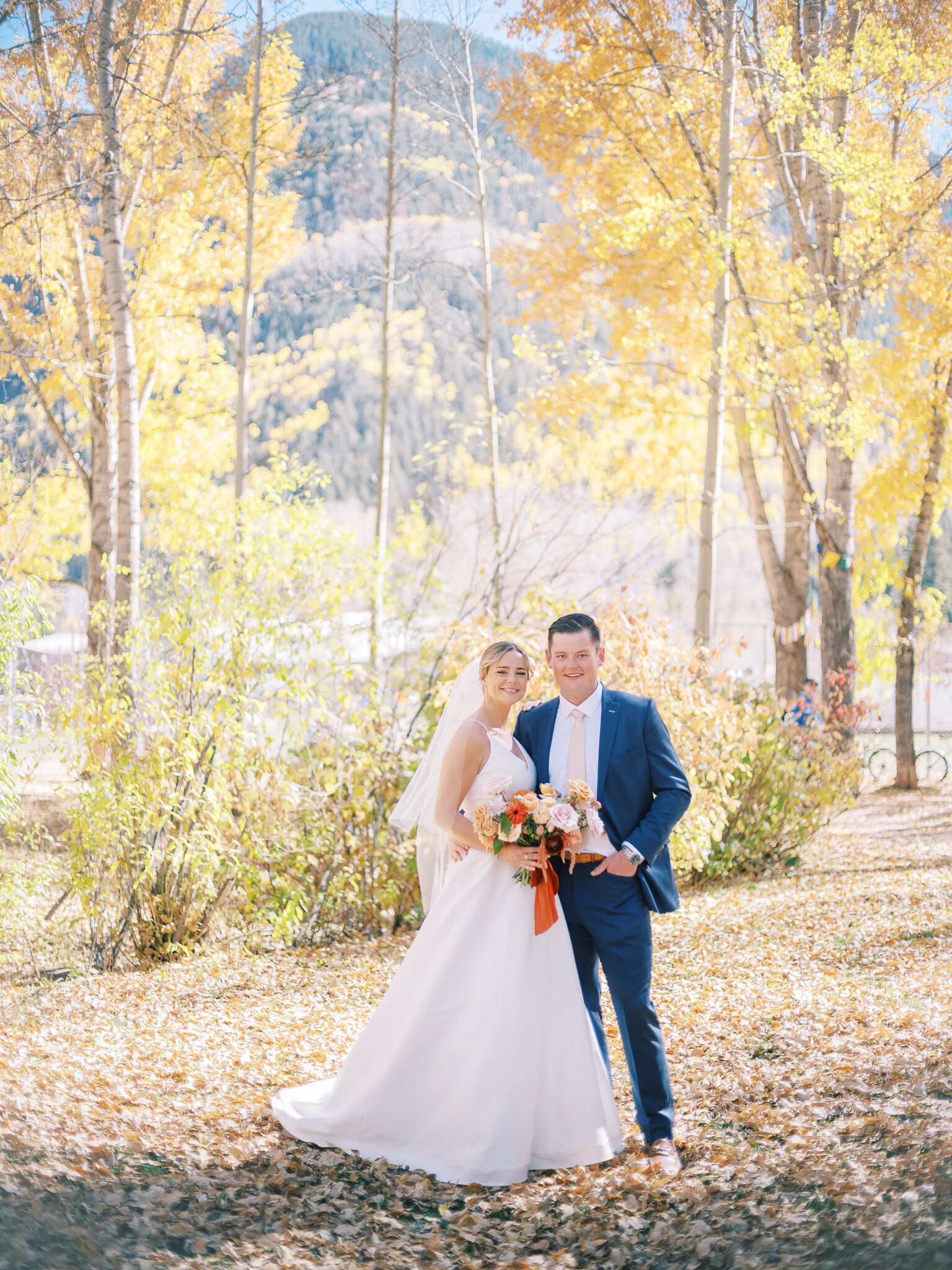 A bride and groom are posing for a picture in the woods.