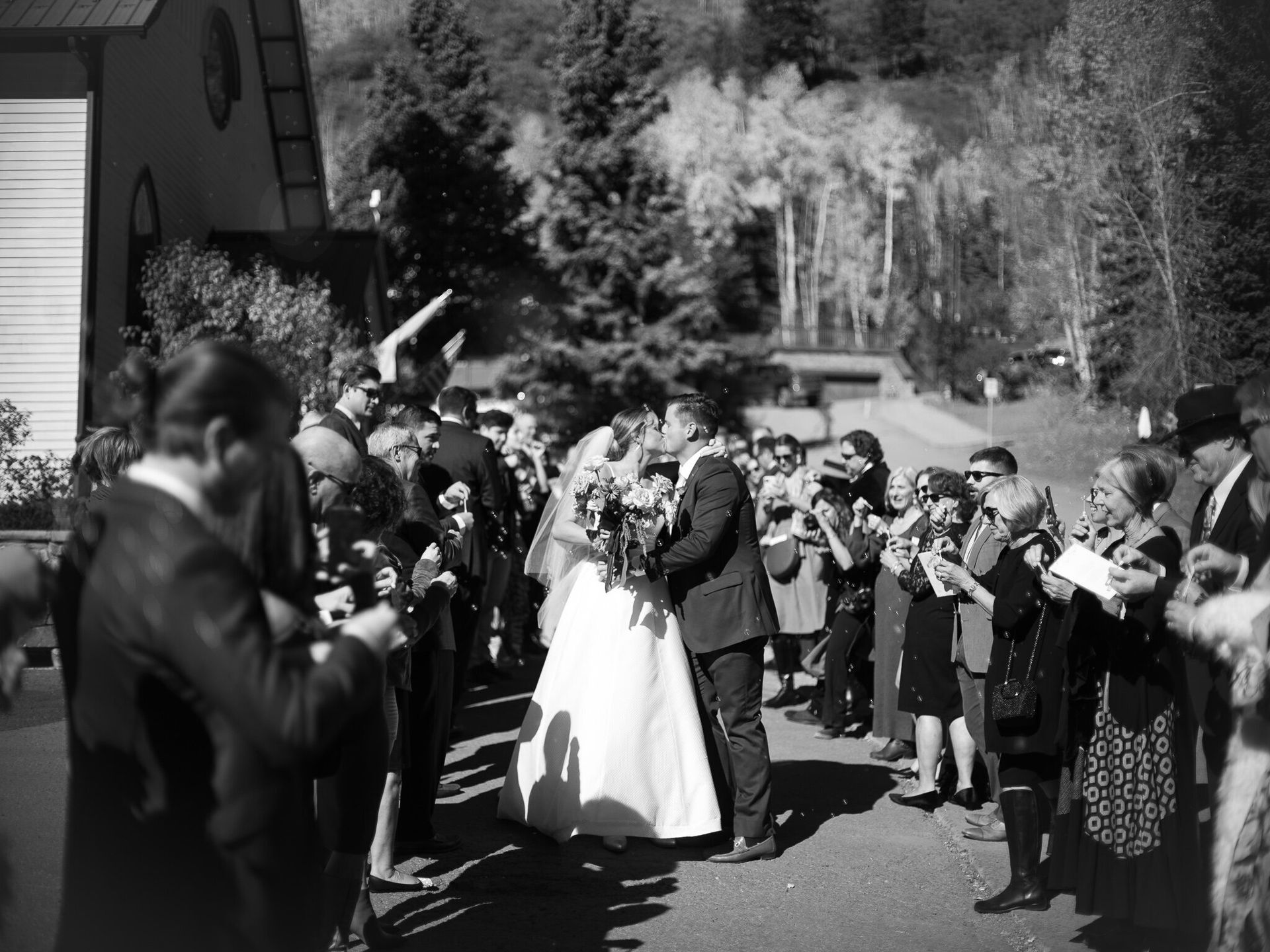 A black and white photo of a bride and groom being congratulated by their wedding guests.