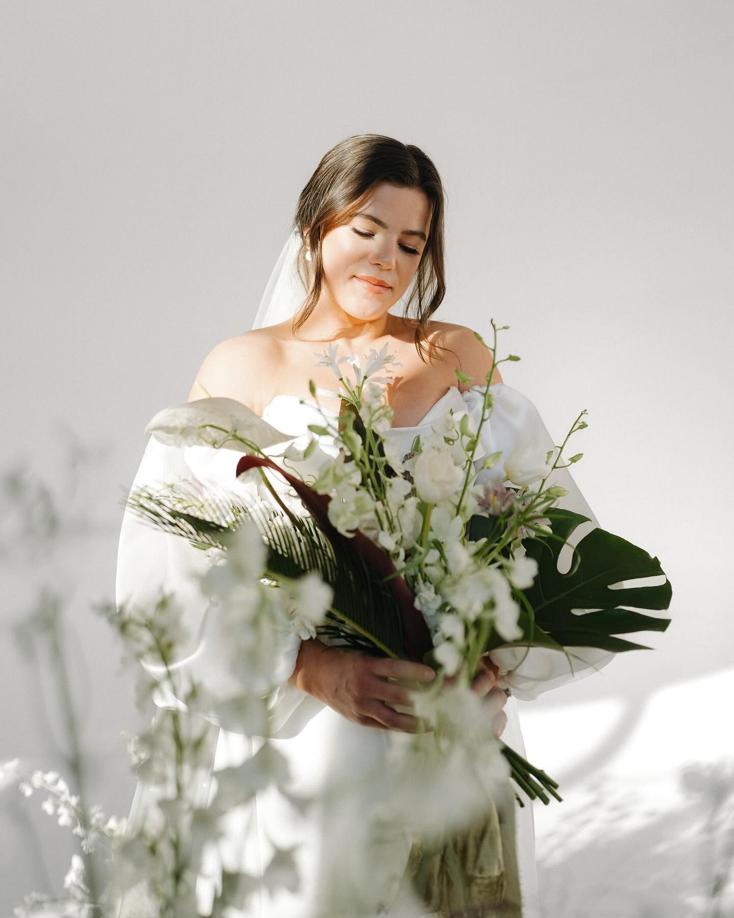 A bride in a white dress is holding a bouquet of flowers.