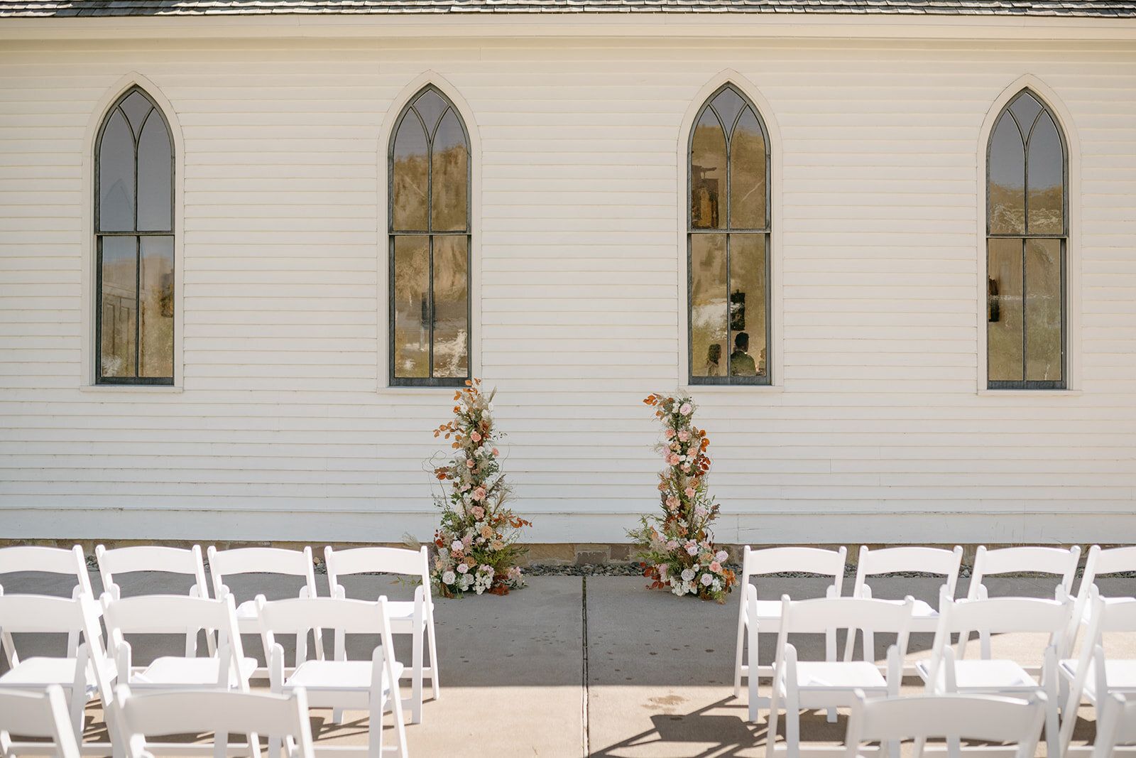 A row of white chairs are lined up in front of a white church.