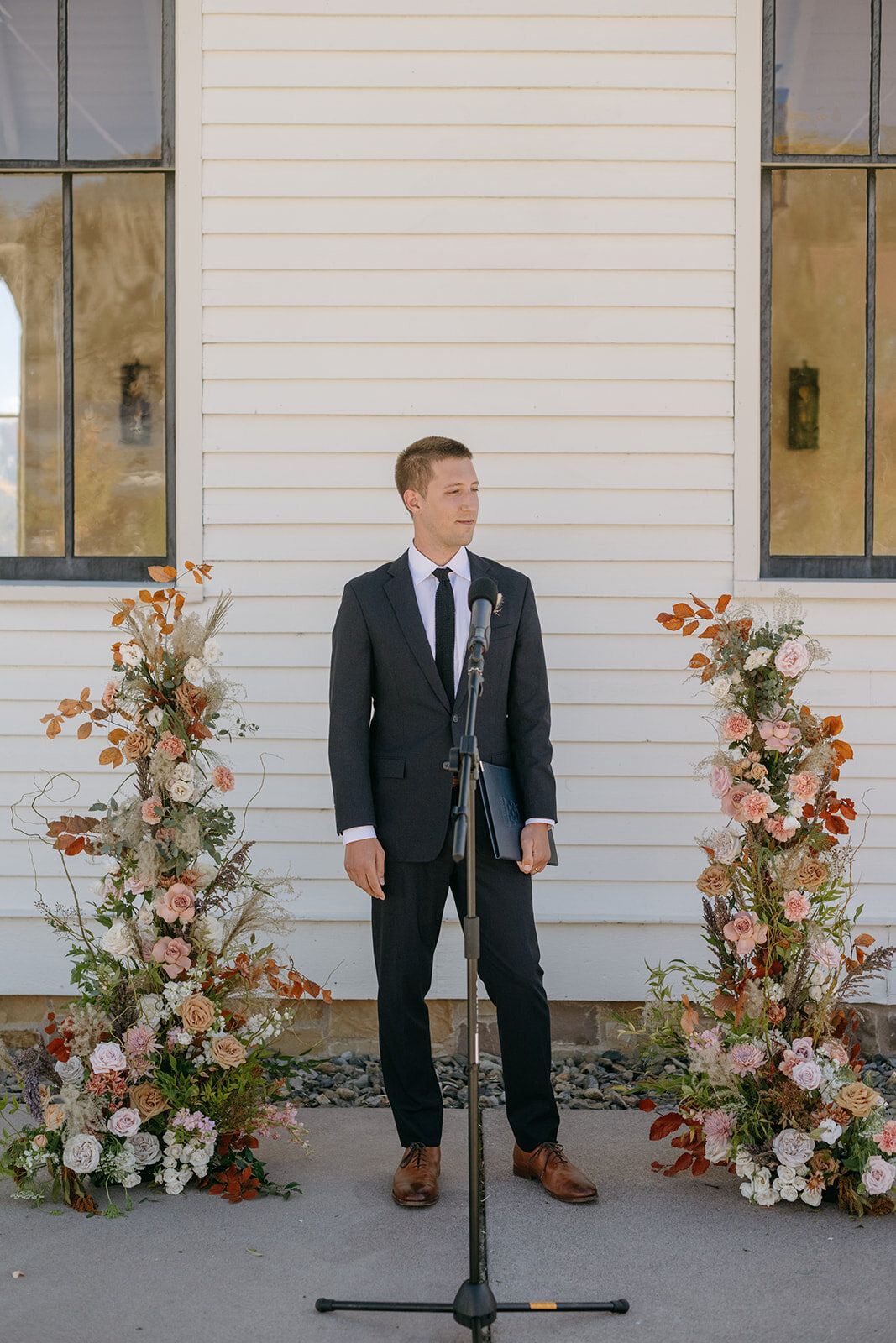 A man in a suit and tie is standing in front of a microphone.