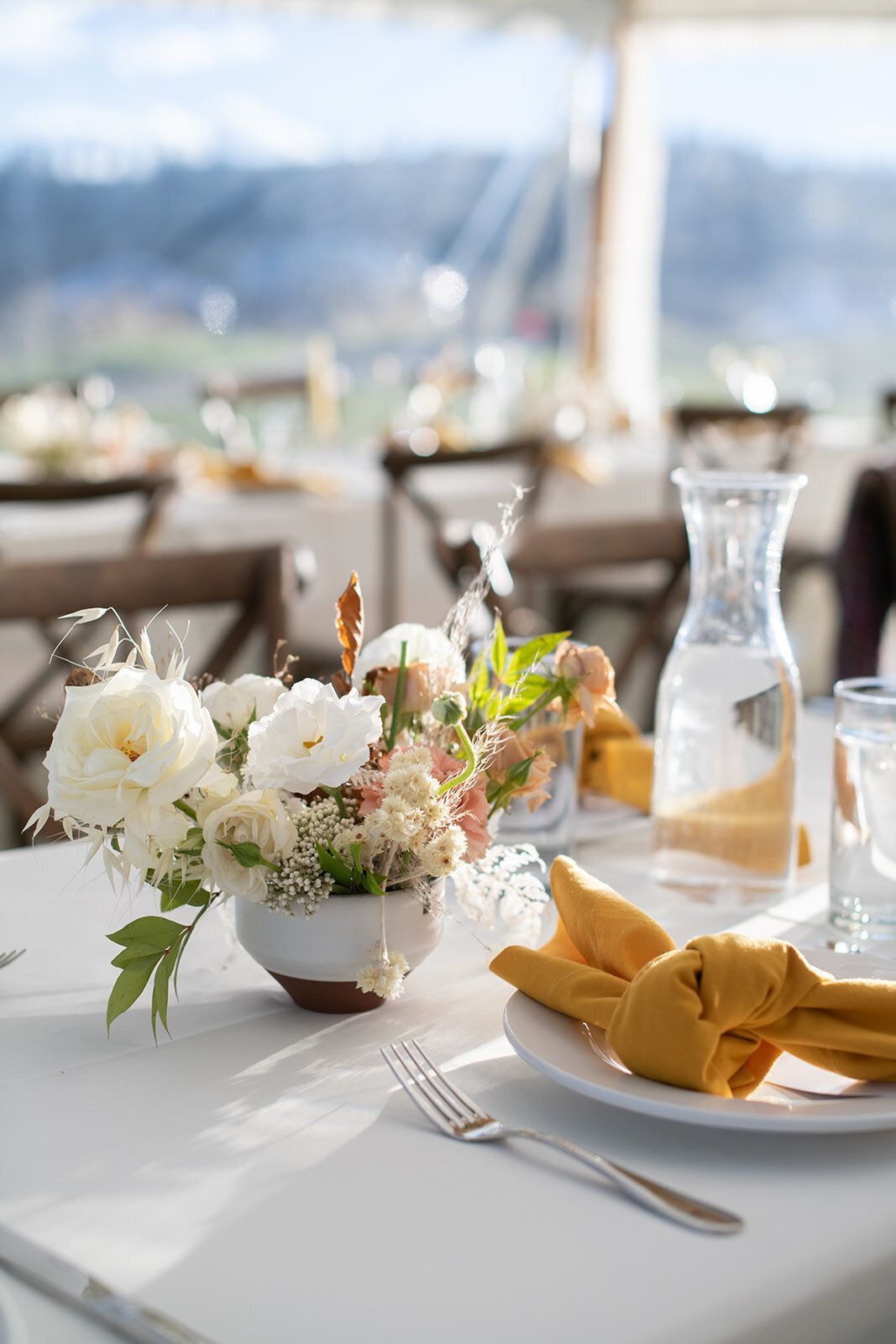 A table set for a wedding reception with a vase of flowers on it.