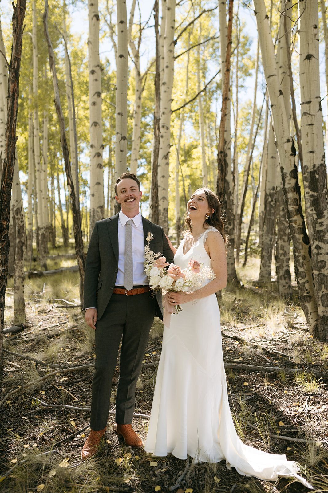 A bride and groom are posing for a picture in the woods.