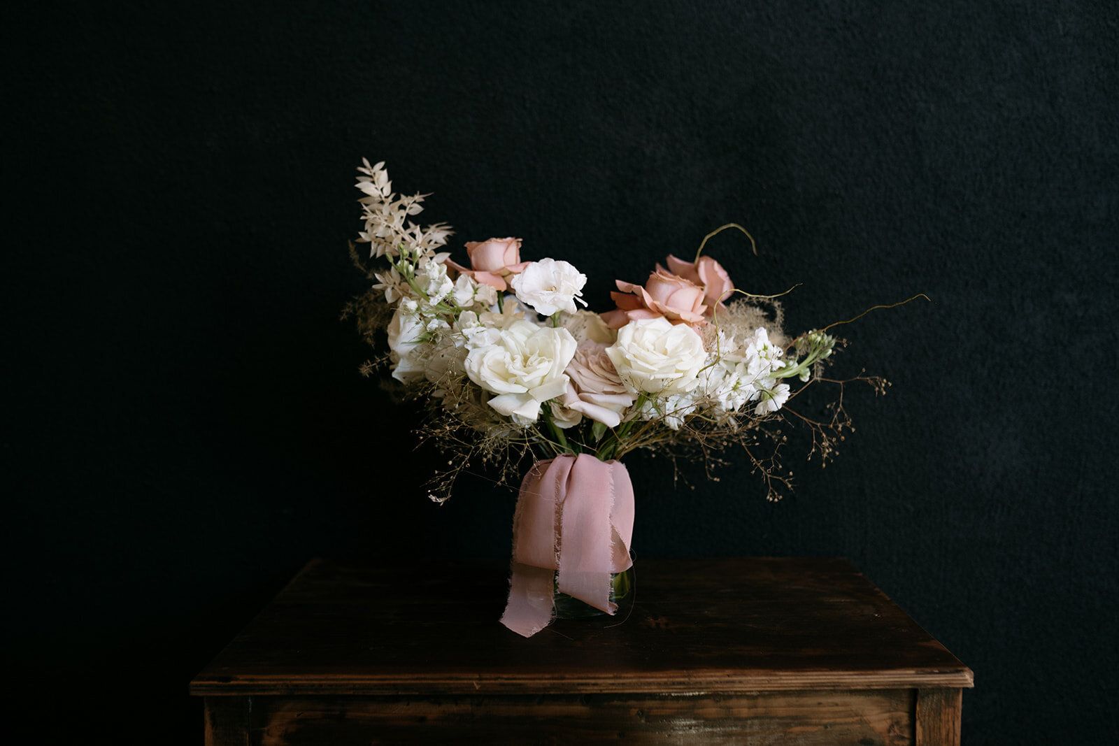 A bouquet of flowers is sitting on a wooden table.