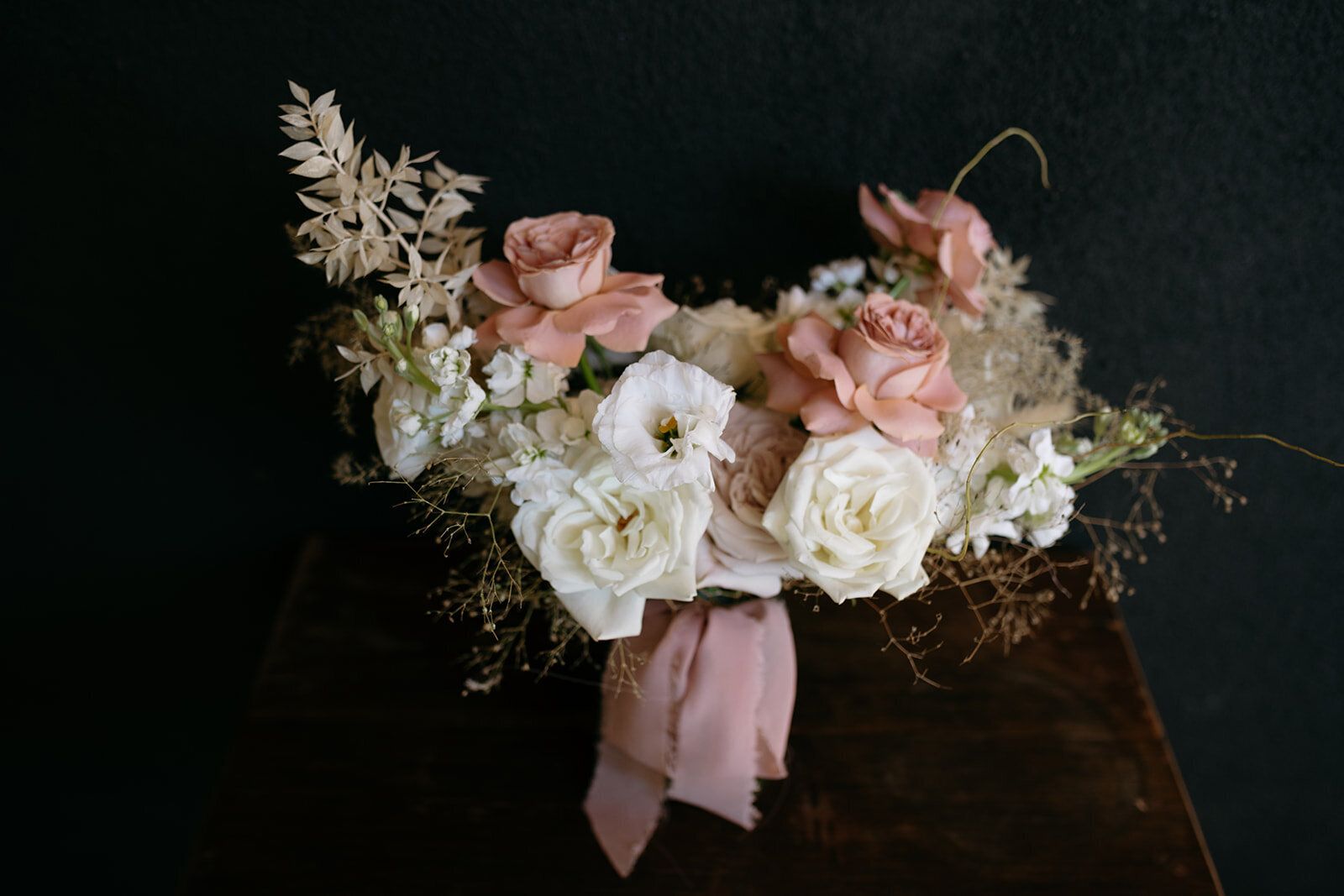 A bouquet of flowers is sitting on a wooden table.