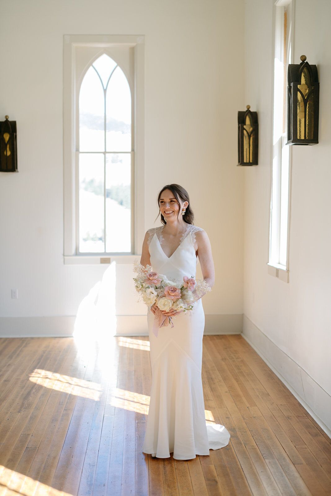 A bride in a wedding dress is standing in a church holding a bouquet of flowers.