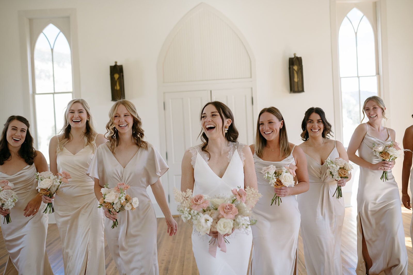 A bride and her bridesmaids are walking in a church.