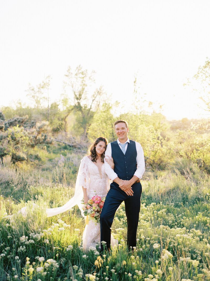 A bride and groom are posing for a picture in a field.