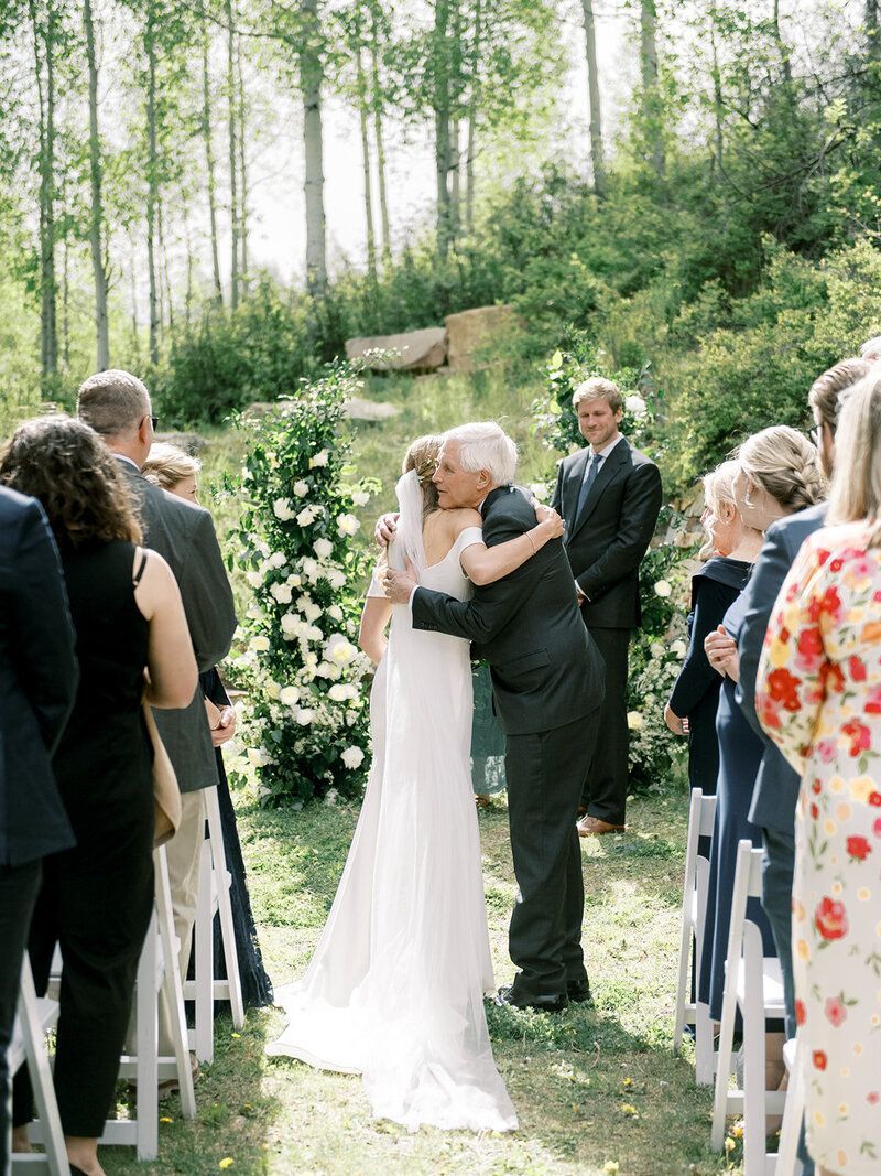 A bride and groom are kissing during their wedding ceremony.
