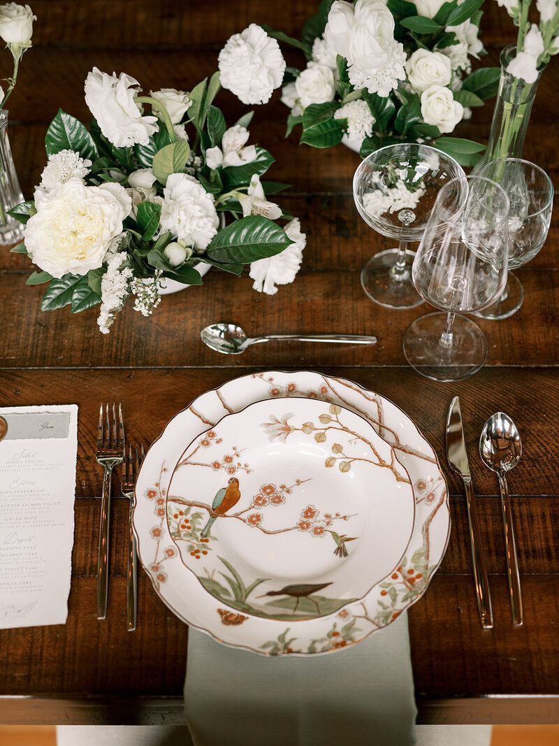 A table setting with plates , silverware , and flowers on it.