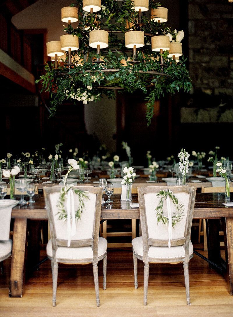 A dining room table with chairs and a chandelier hanging from the ceiling