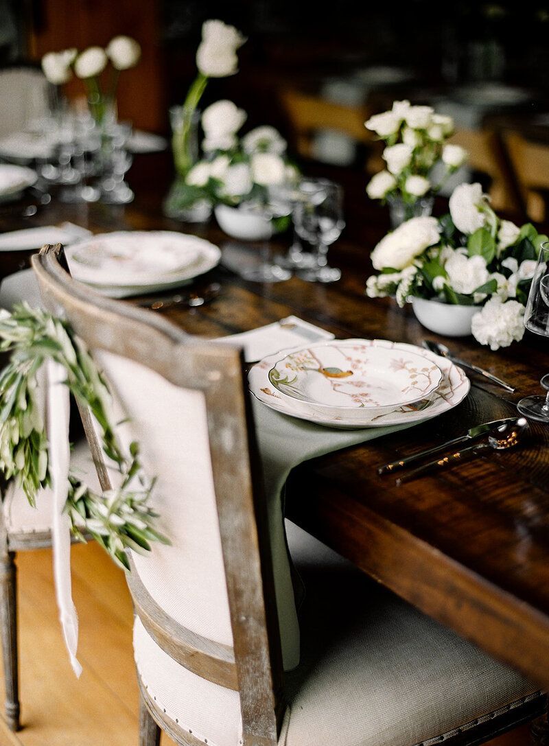 A wooden table with plates , utensils , and flowers on it.
