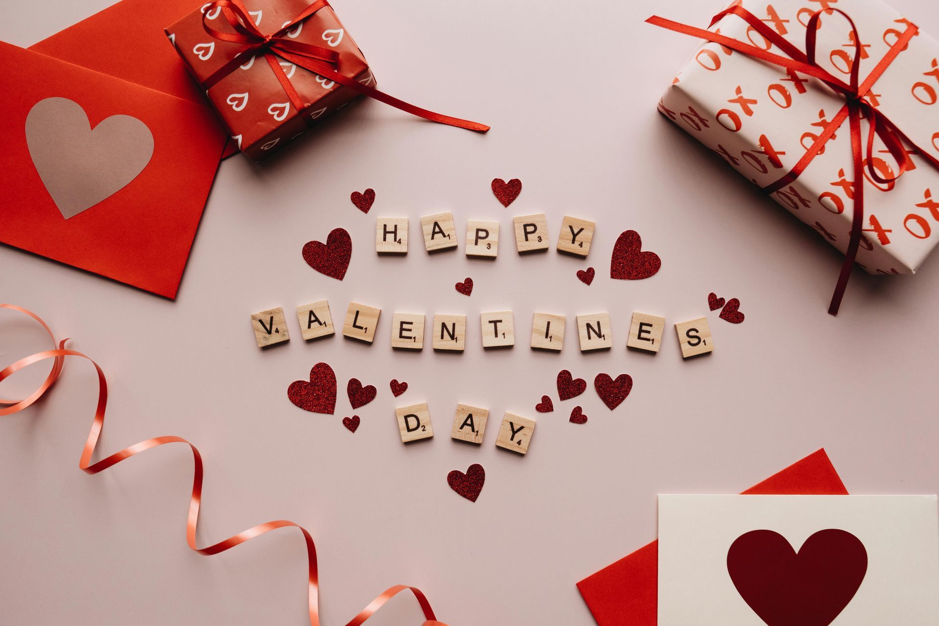 Valentine's Day scene with gifts, hearts, envelopes, ribbon, and scrabble letters spelling 