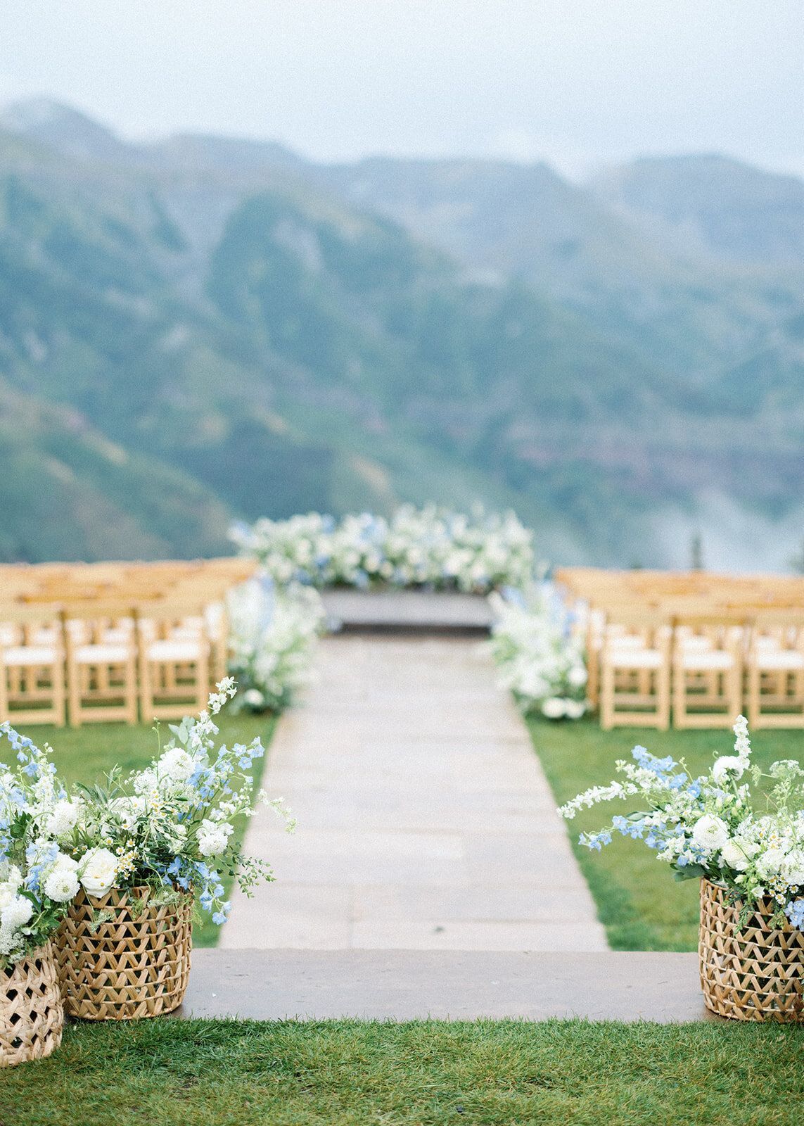 A wedding ceremony is taking place in a field with mountains in the background.