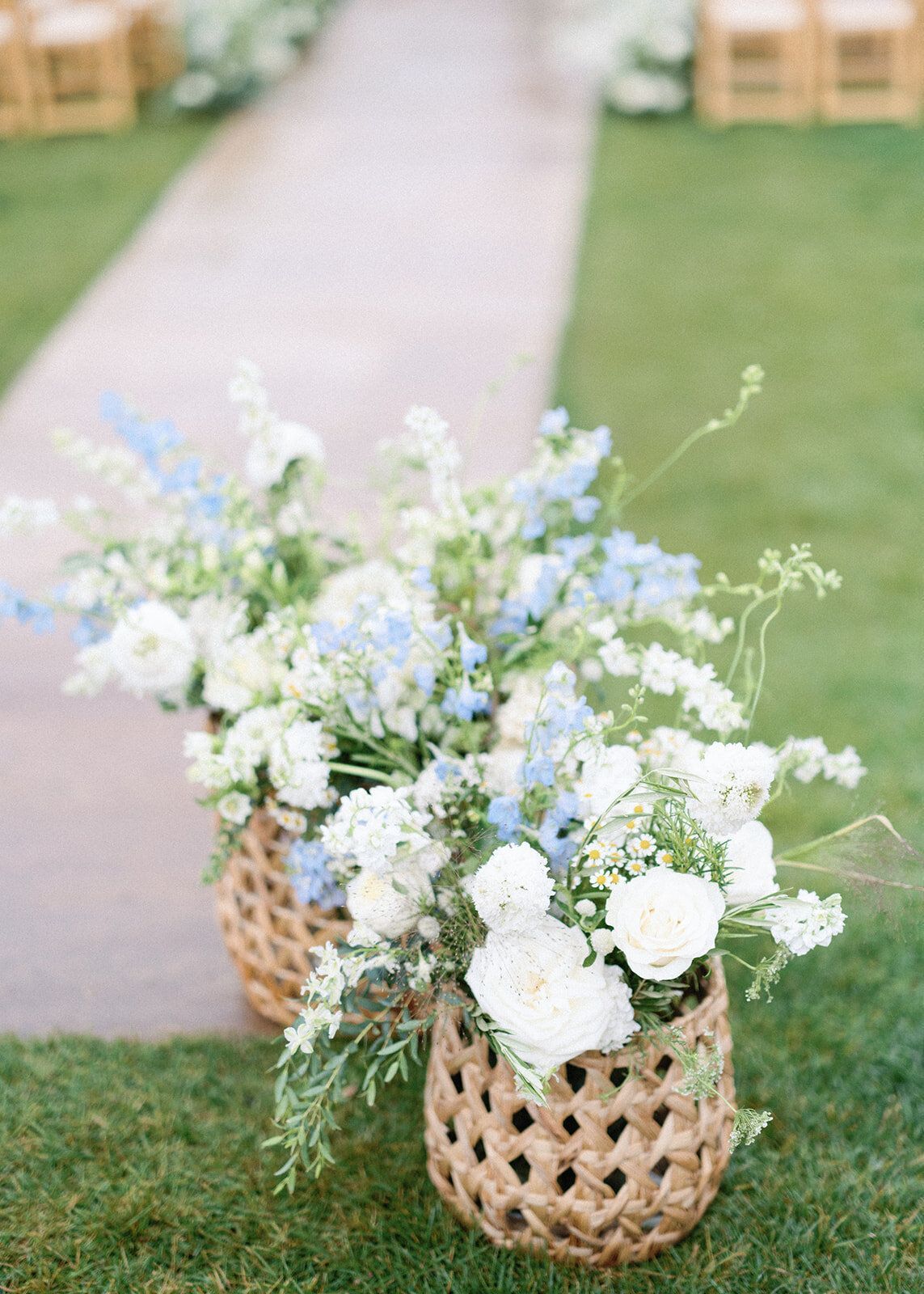 Two baskets filled with white and blue flowers are sitting on top of a lush green field.