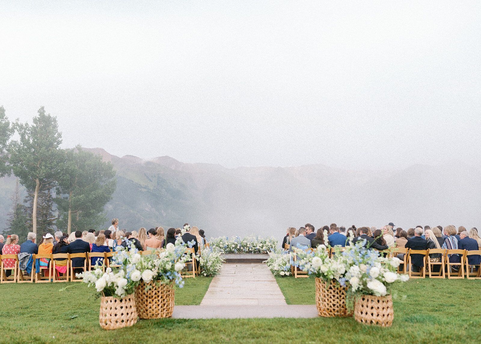 A wedding ceremony is taking place in a field with a lake in the background.