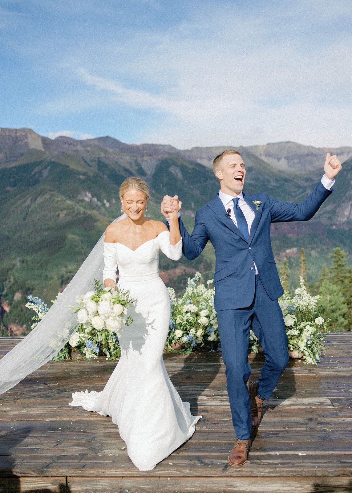 A bride and groom are celebrating their wedding with mountains in the background.