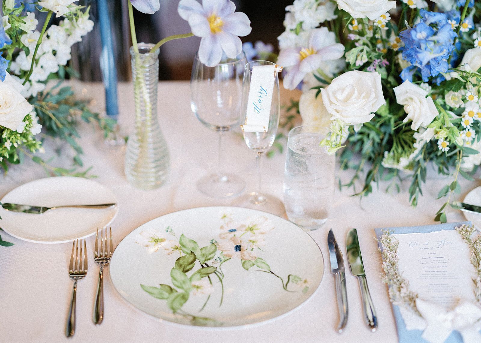 A table set for a wedding reception with plates , silverware , and flowers.