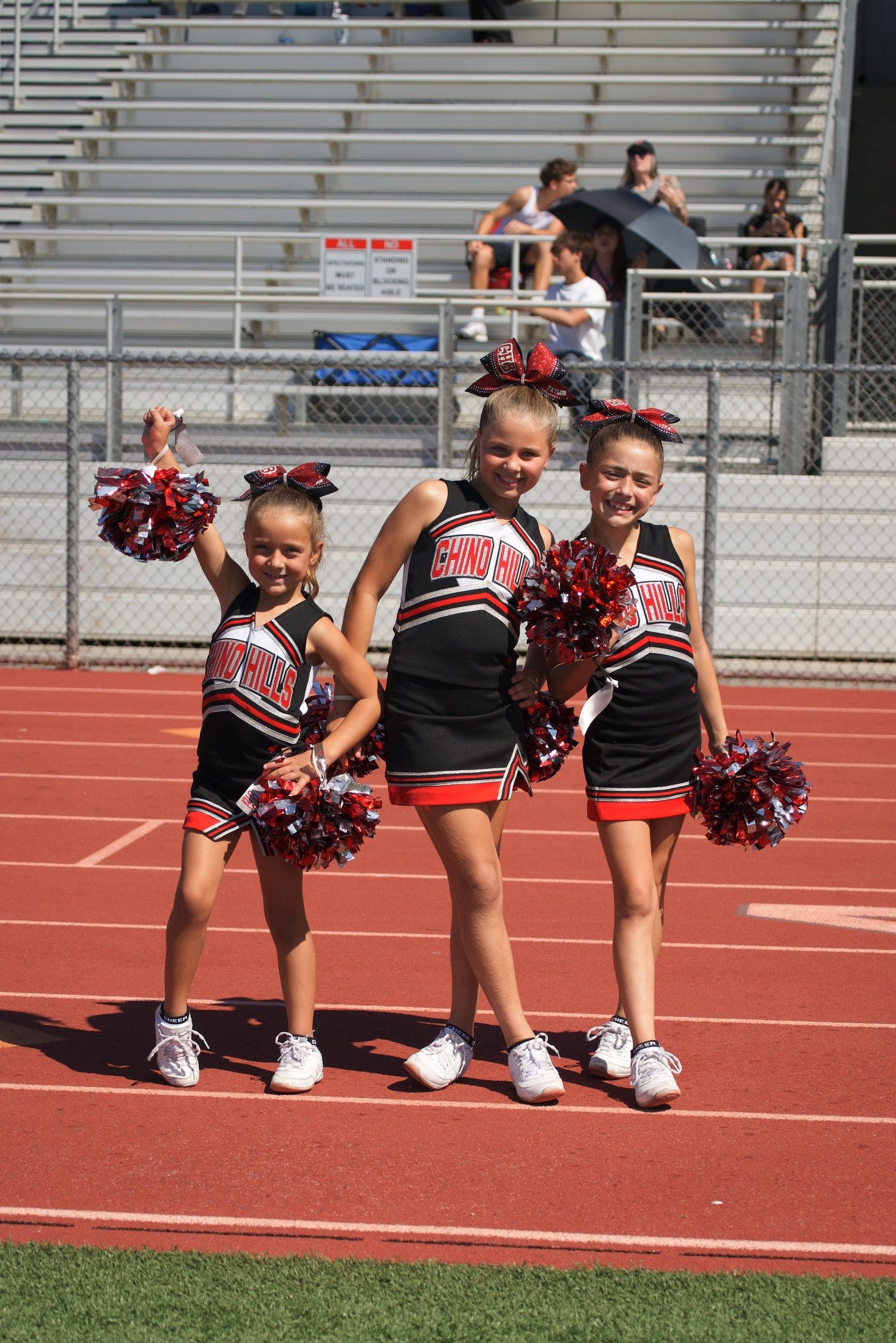 Cheerleader in red uniform performs a backbend on a green and red football field.