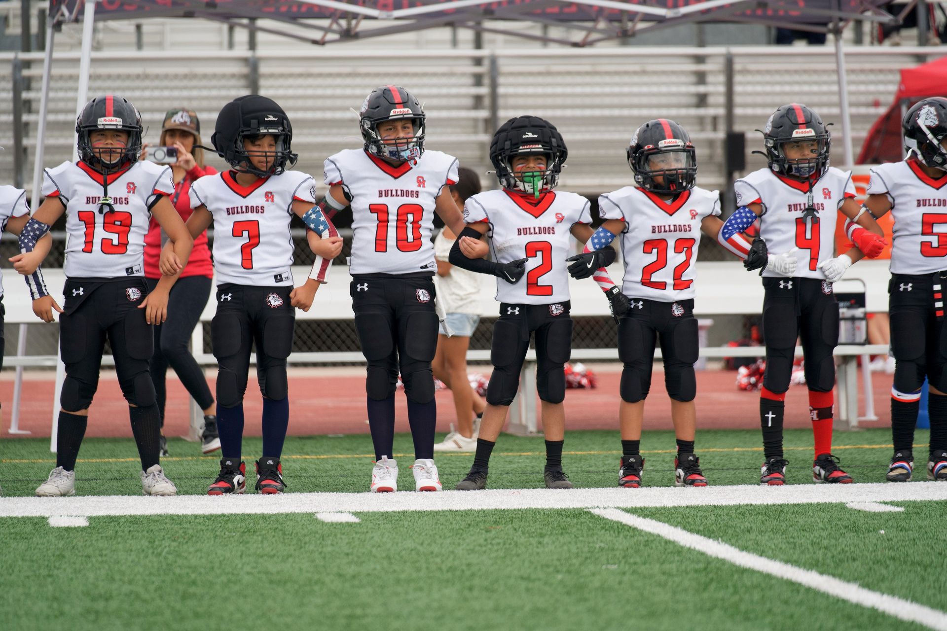 Football player in silver uniform runs with ball on a green field.