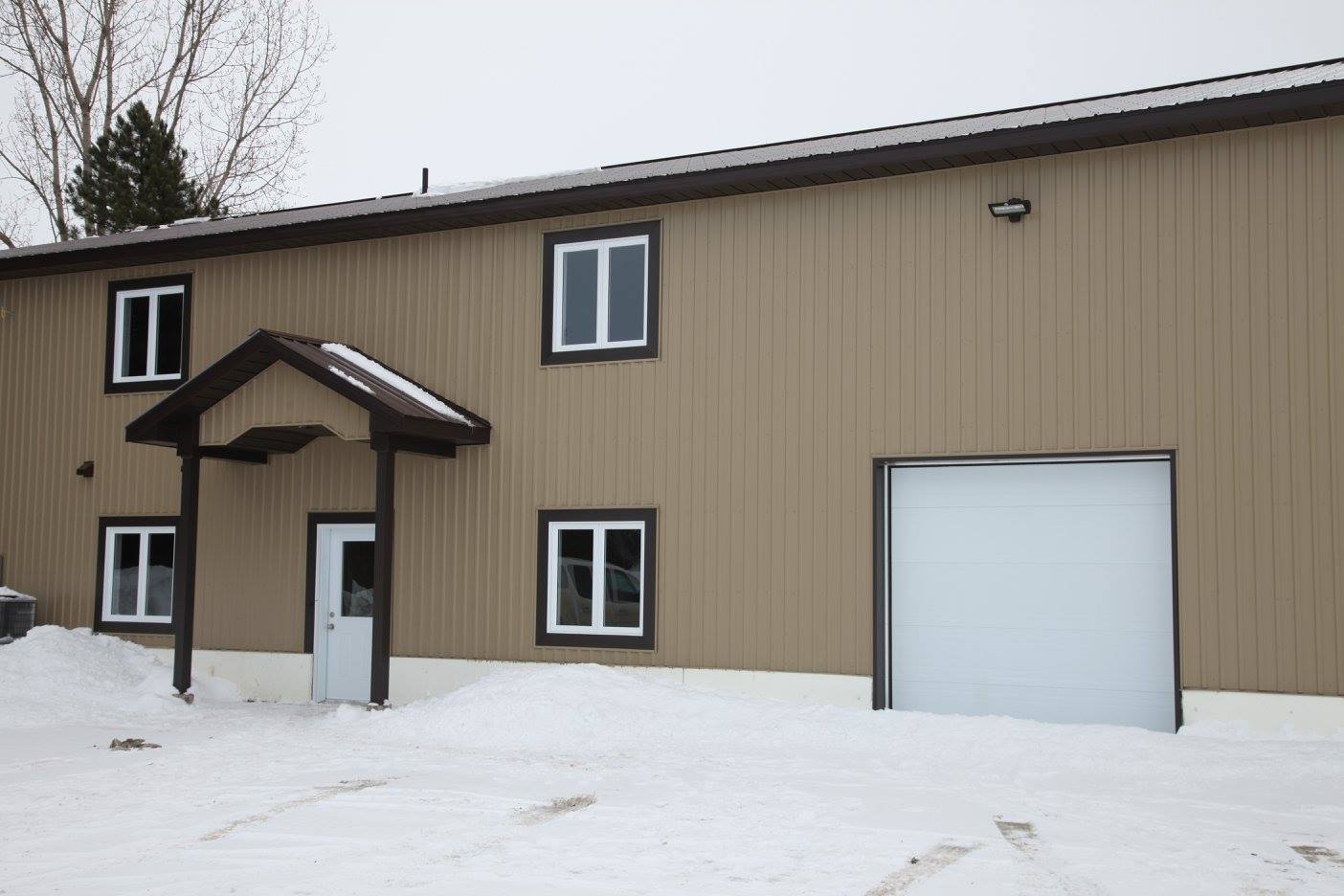 Un bâtiment avec une porte de garage et un porche dans la neige