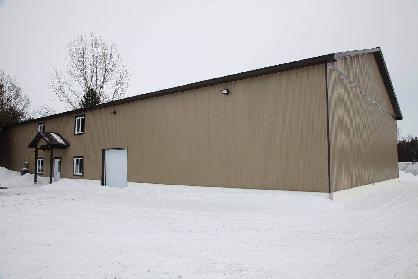 Un grand bâtiment marron avec une porte de garage dans la neige