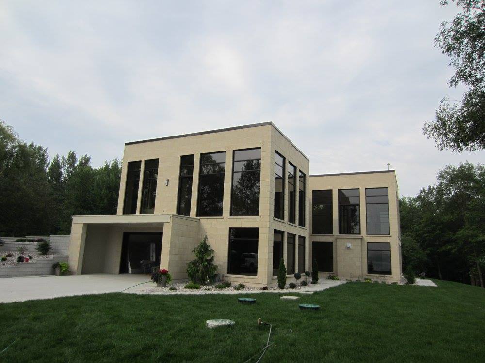 Une grande maison avec beaucoup de fenêtres est entourée d'arbres