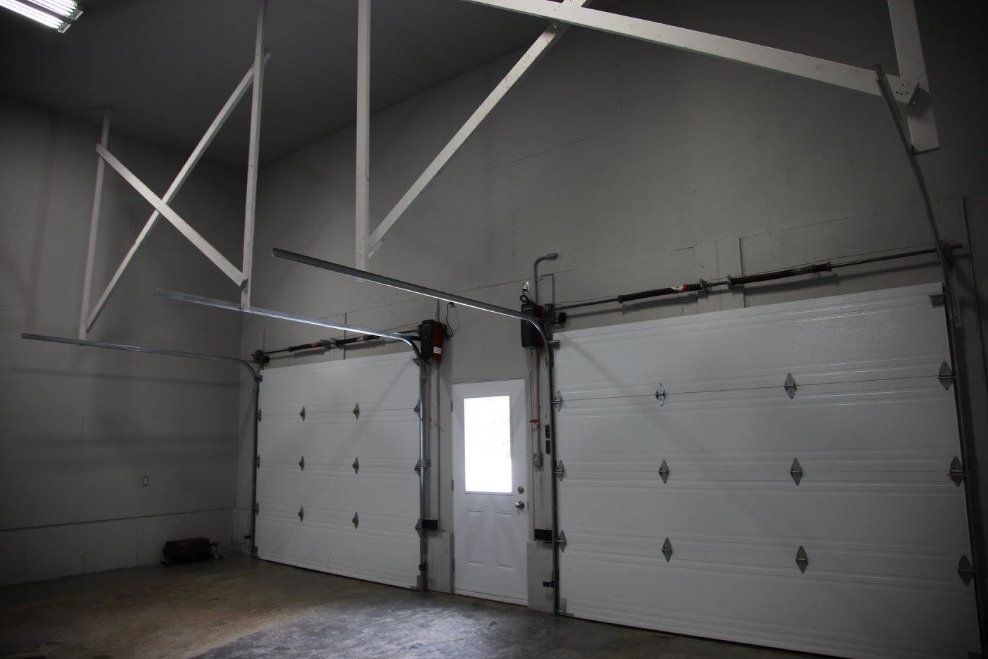 Un garage avec deux portes de garage blanches et une fenêtre.