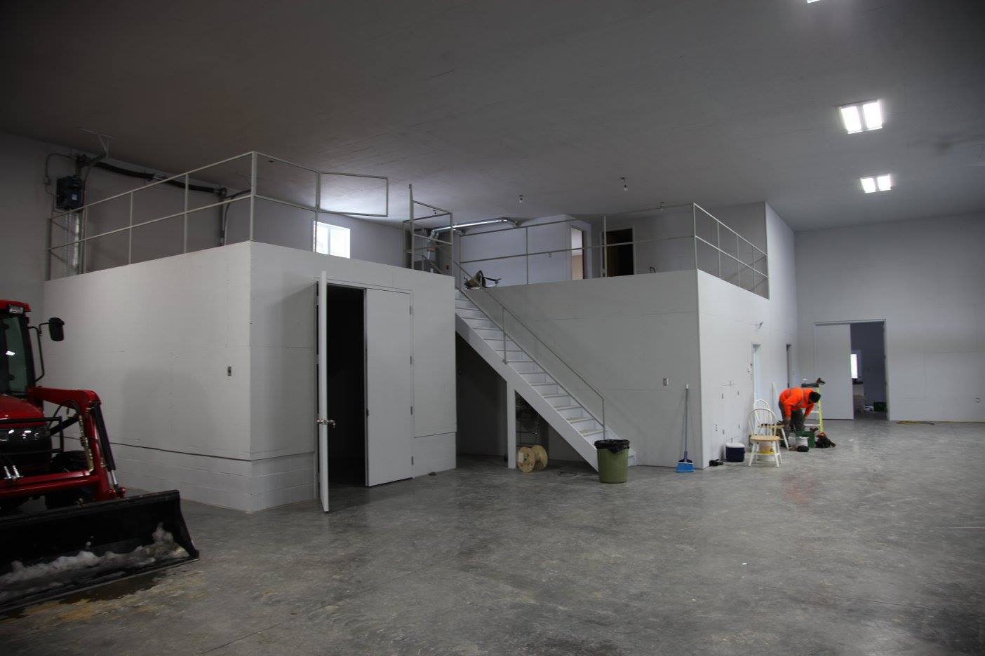 Un grand entrepôt vide avec des escaliers menant au deuxième étage.