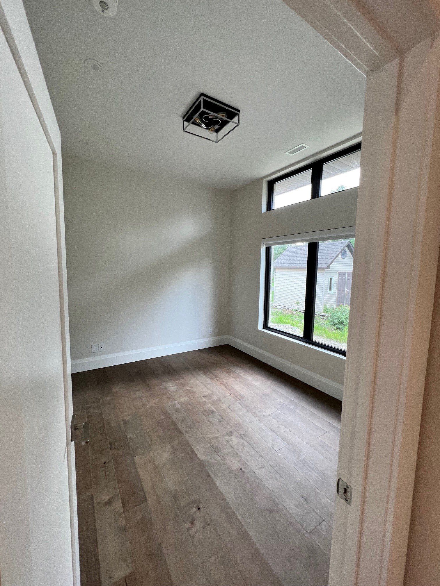 Une pièce vide avec du parquet et deux fenêtres.