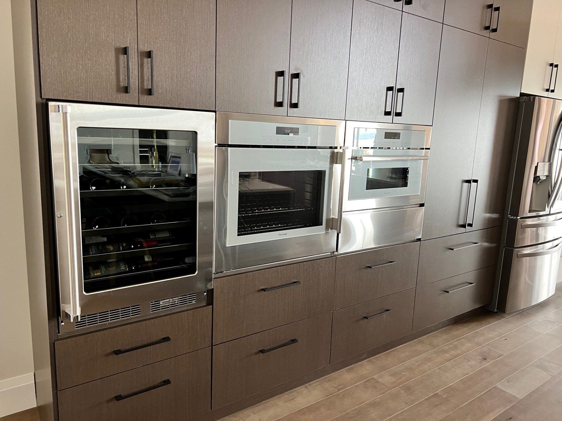 Une cuisine avec électroménagers en acier inoxydable et armoires en bois.