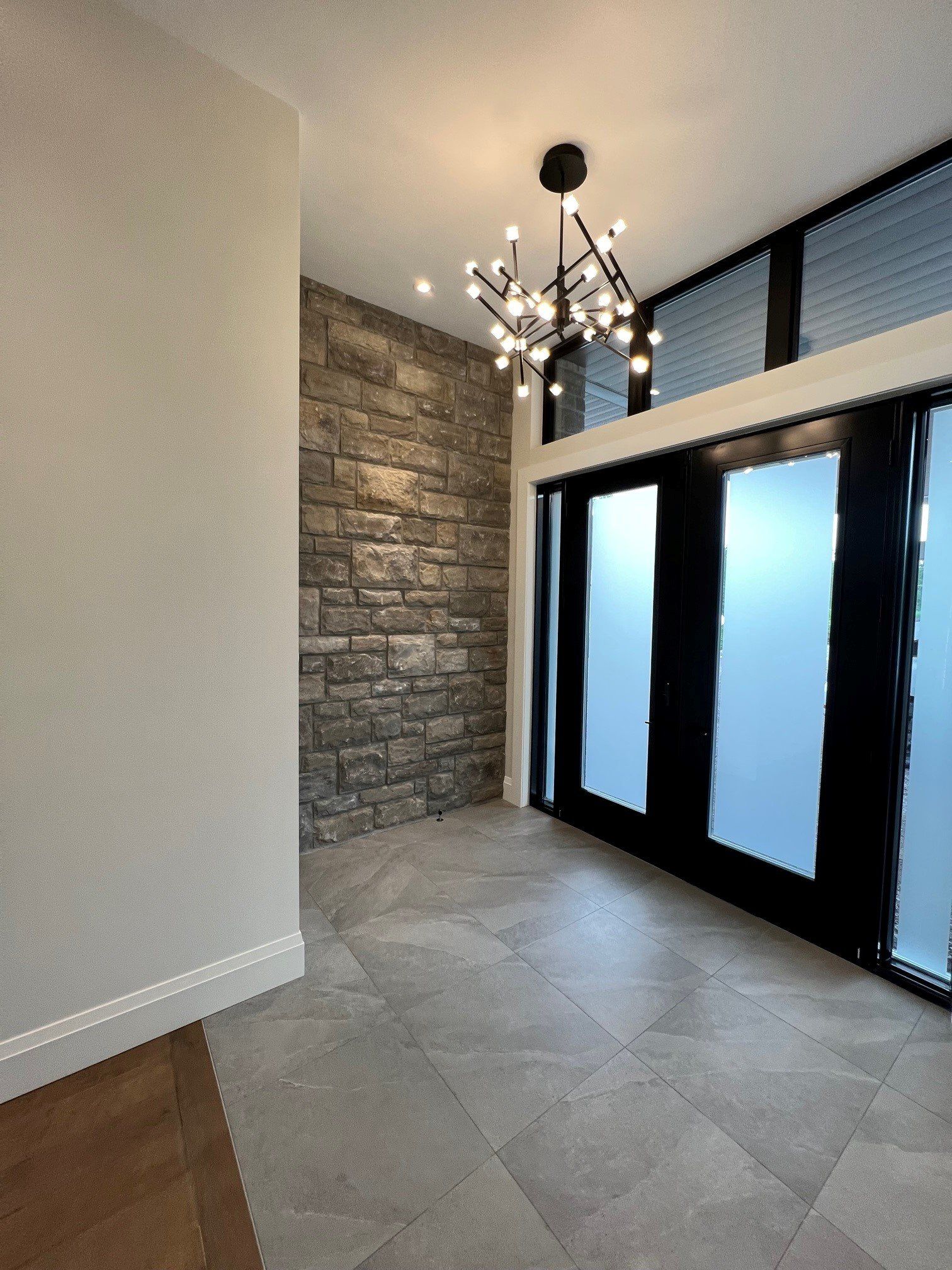 Un couloir vide avec un mur de pierre et un lustre suspendu au plafond.