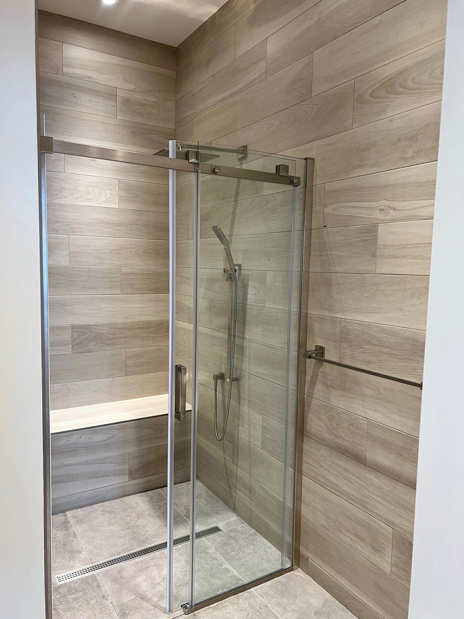 Une salle de bain avec douche à l'italienne avec porte coulissante en verre.