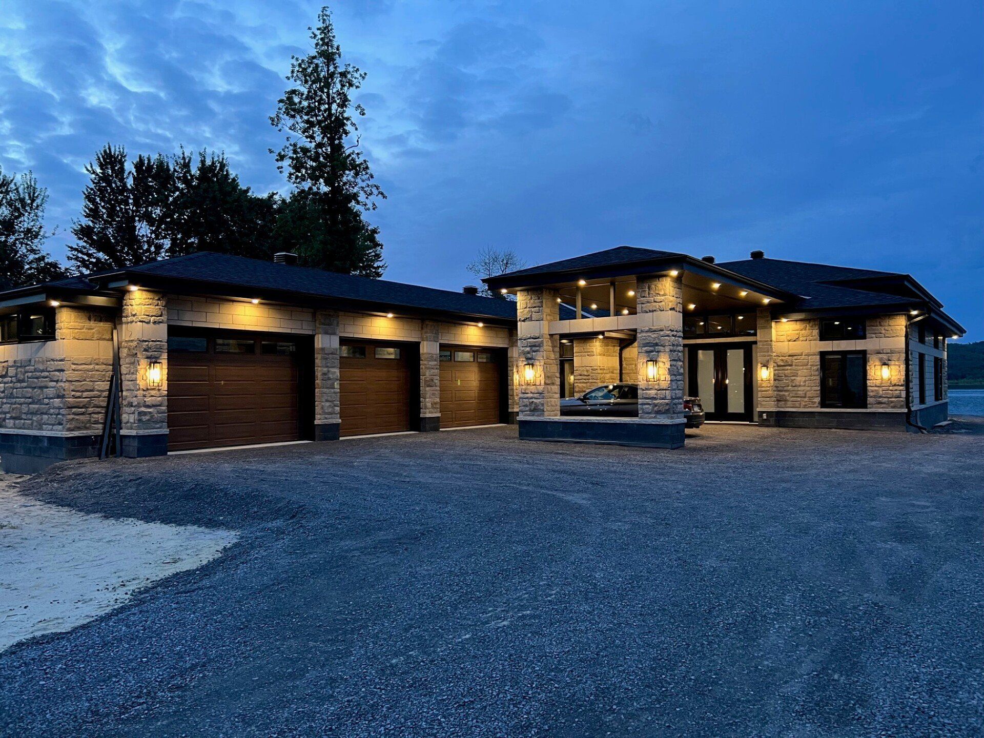 Une grande maison avec deux garages est éclairée la nuit.