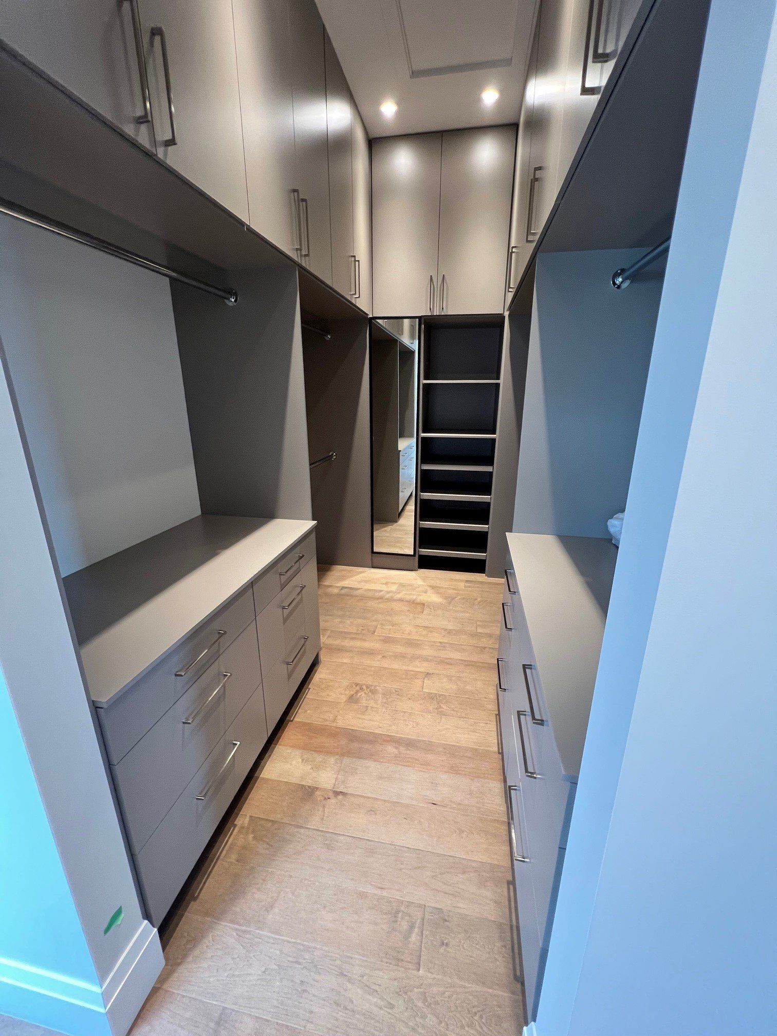 Un dressing avec beaucoup d'armoires et de tiroirs et un miroir.