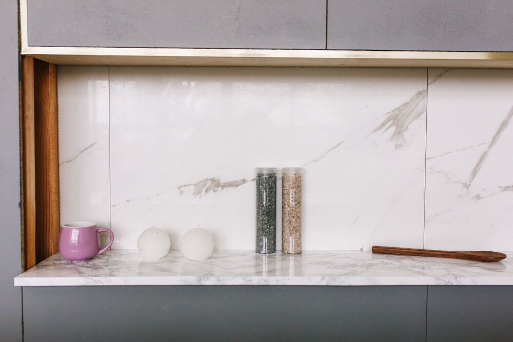 A Marble Counter Top With a Pink Cup, Salt and Pepper Shakers, and a Wooden Spoon — Sunny Tiling Co in Mount Coolum, QLD