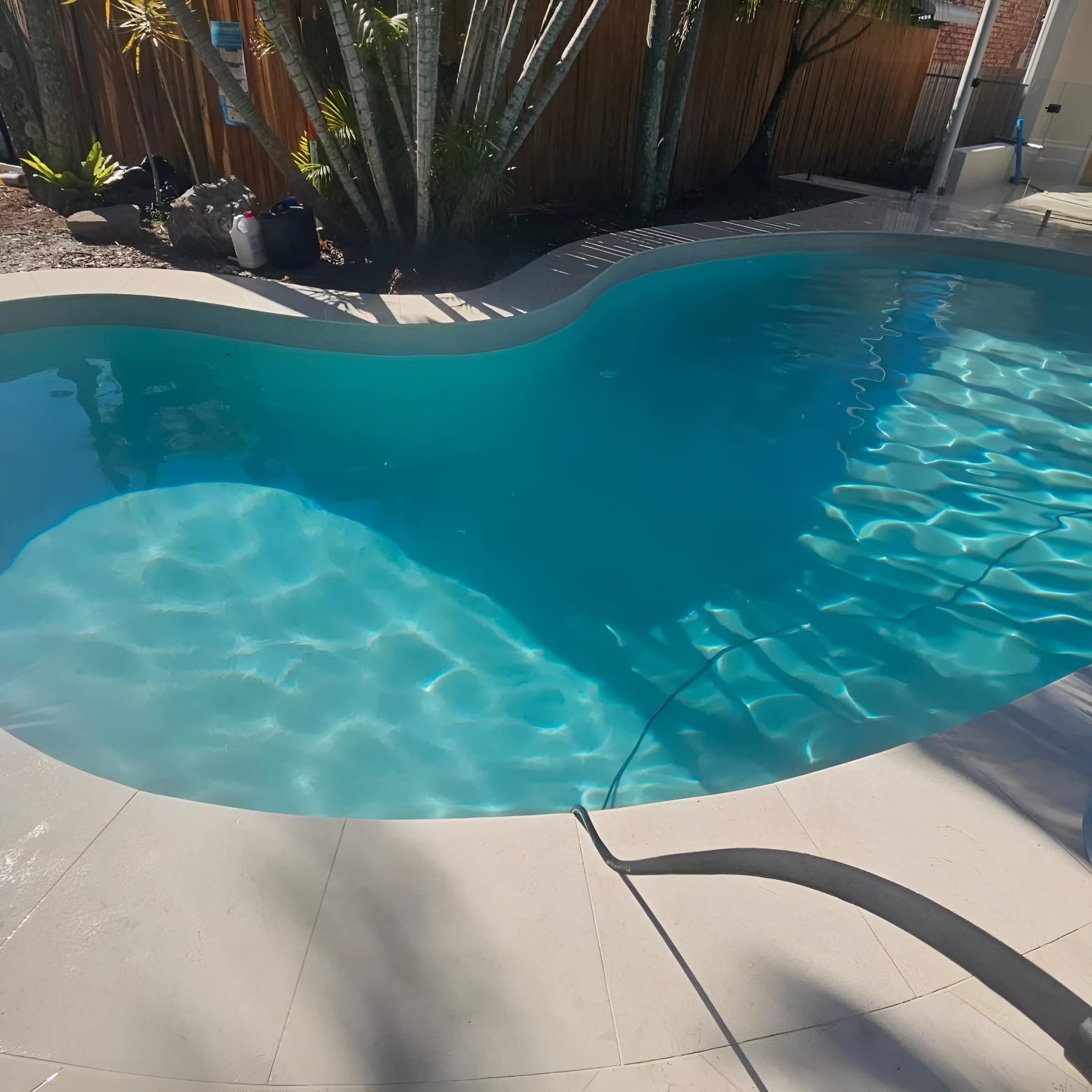 A Large Swimming Pool With a Fence in the Background — Sunny Tiling Co in Mount Coolum, QLD