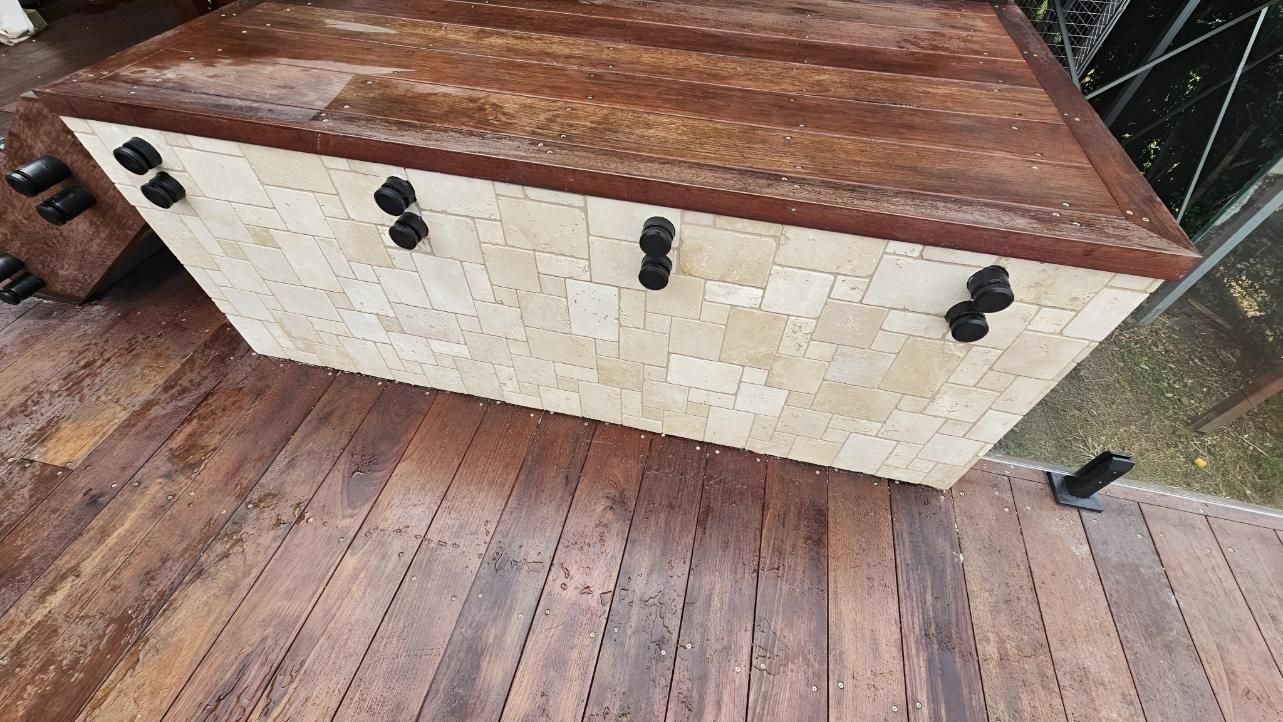 Wooden bench with light stone facade and dark hardware, on a wooden deck — Sunny Tiling Co in Mount Coolum, QLD