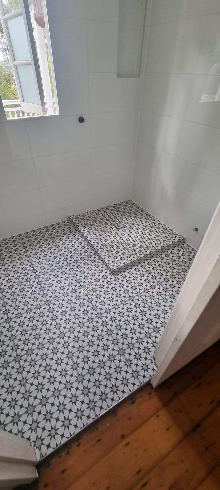 A small, white-walled room with patterned floor covering, wooden floor, and window — Sunny Tiling Co in Mount Coolum, QLD