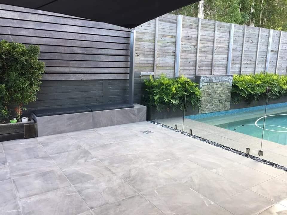 Patio With Pool,  Grey Tiles, Glass Fence, Wooden Wall and Greenery — Sunny Tiling Co in Mount Coolum, QLD