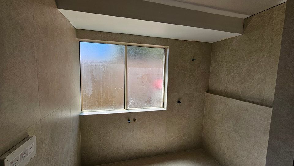 Empty room with window, covered with frosted glass.  Tan tiled walls.