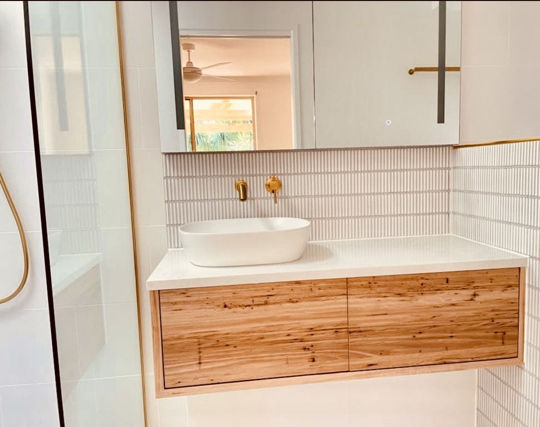 Modern bathroom with wood vanity, white vessel sink, gold fixtures, and textured tile backsplash — Sunny Tiling Co in Mount Coolum, QLD